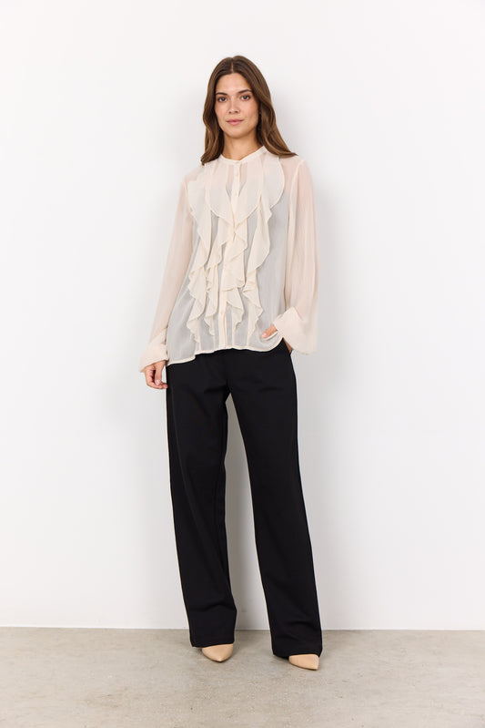Woman wearing a white blouse and black pants against a white background