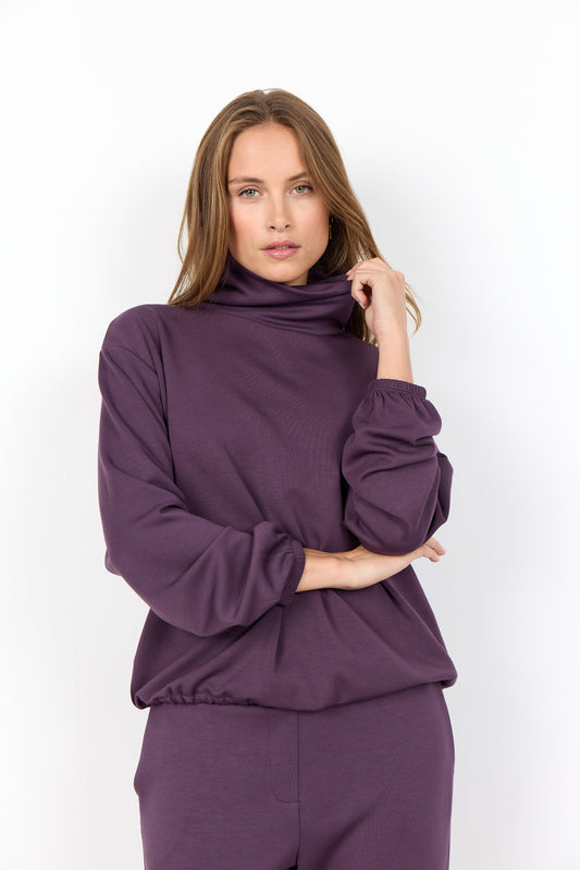 Woman wearing a purple outfit against a white background
