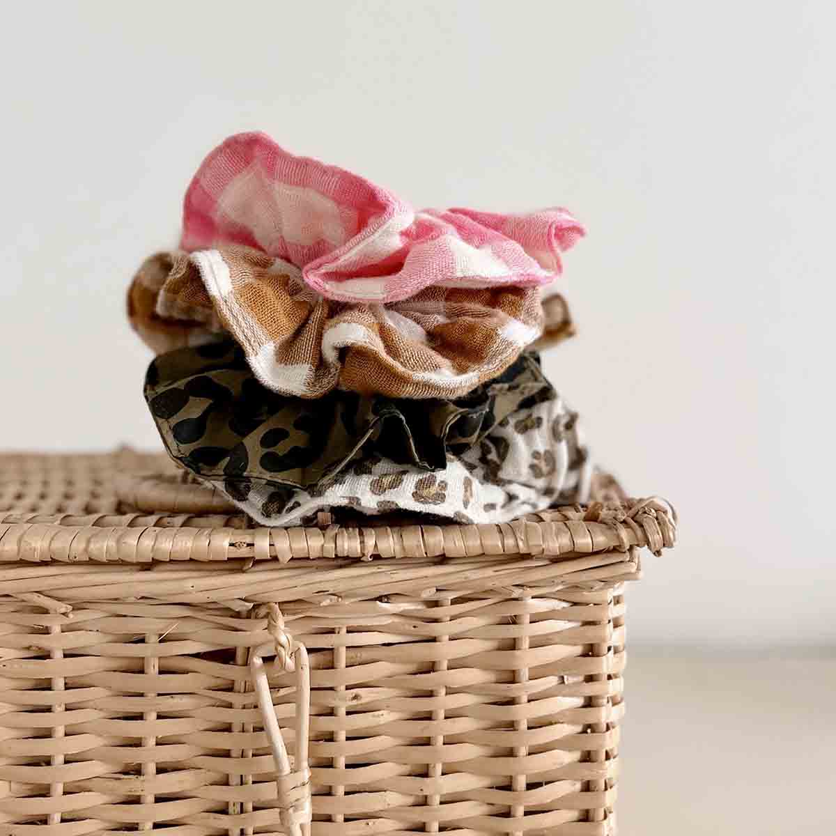 Stack of colorful scrunchies on a wicker basket with a white background