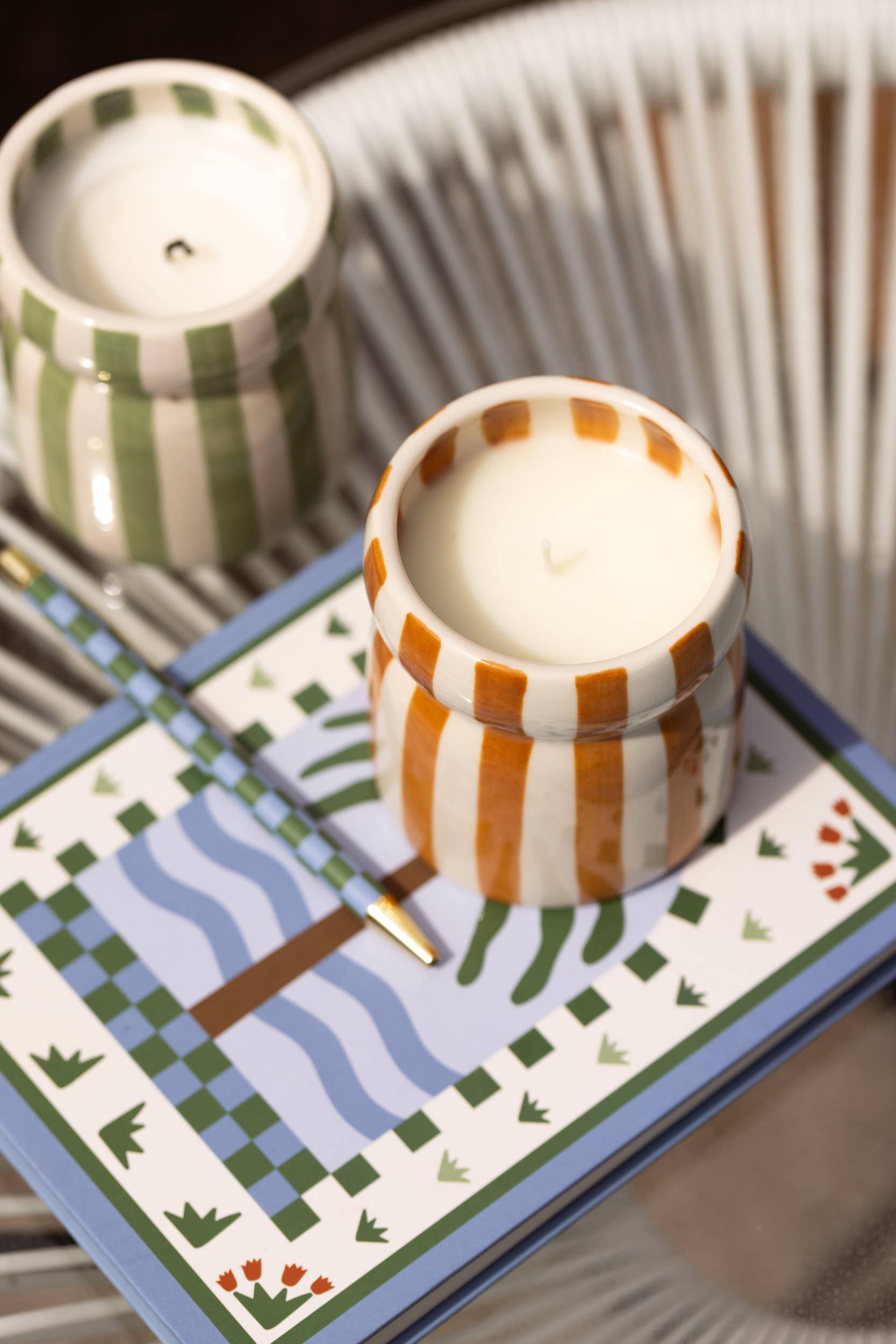 Two striped candles on a decorative tray with a patterned background