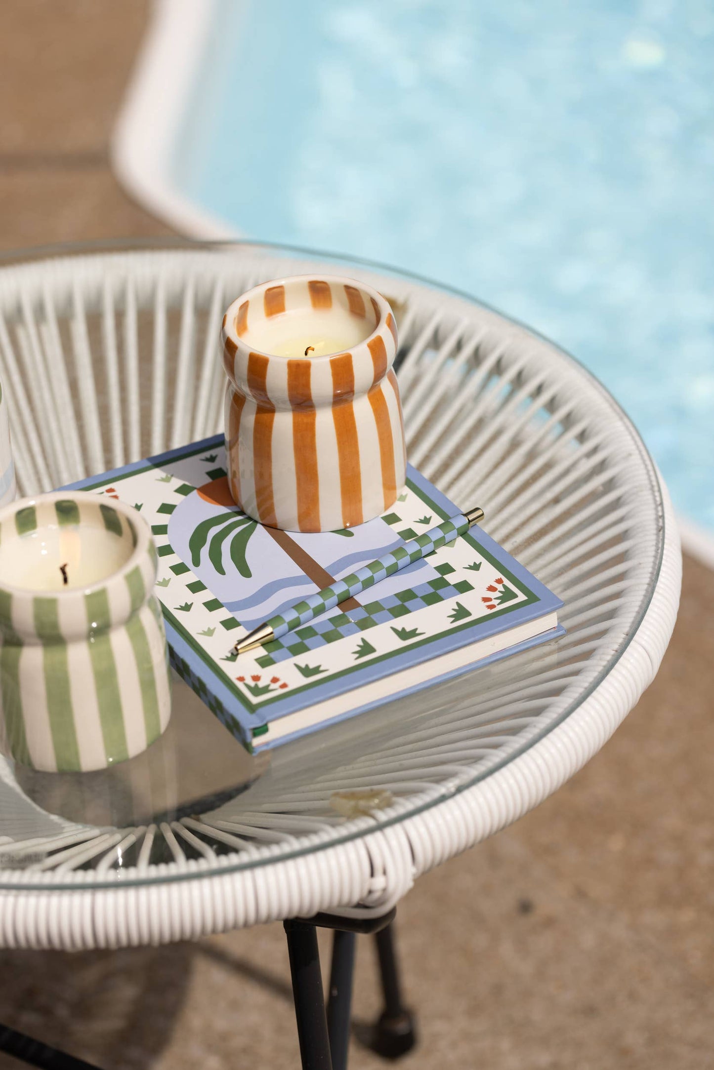 Two candles on a decorative book with a pool in the background
