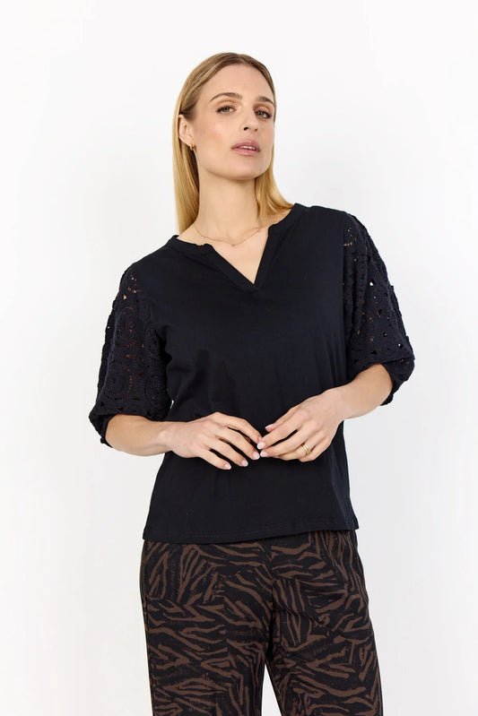 Woman wearing a black top with sequin embellishments on a white background