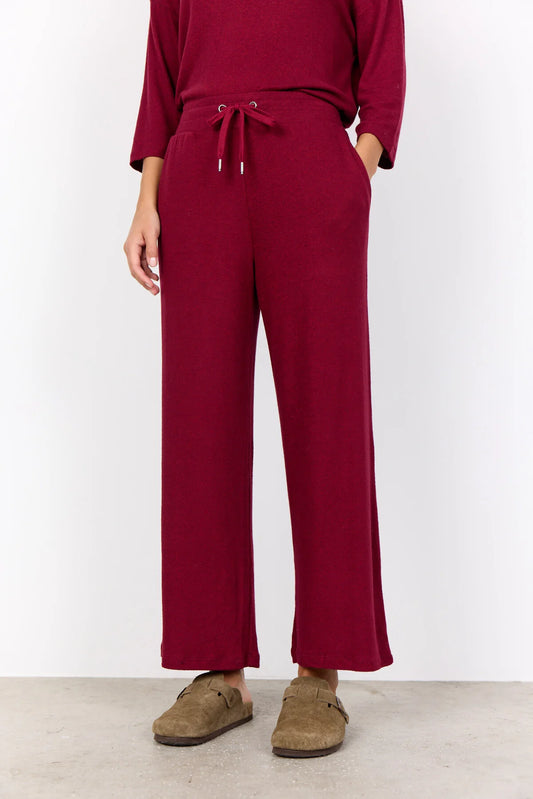 Person wearing a burgundy outfit with wide-leg pants and a matching top on a white background