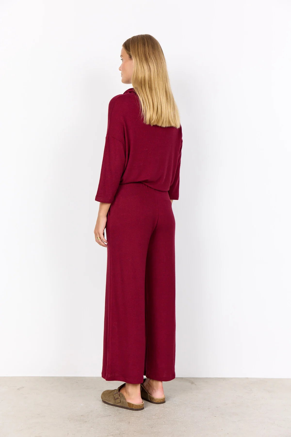 Woman wearing a burgundy outfit with wide-leg pants on a white background