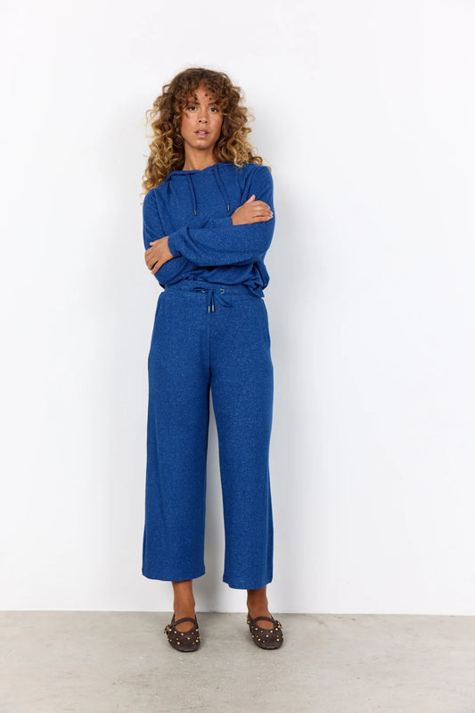 Woman wearing a blue outfit standing against a white background