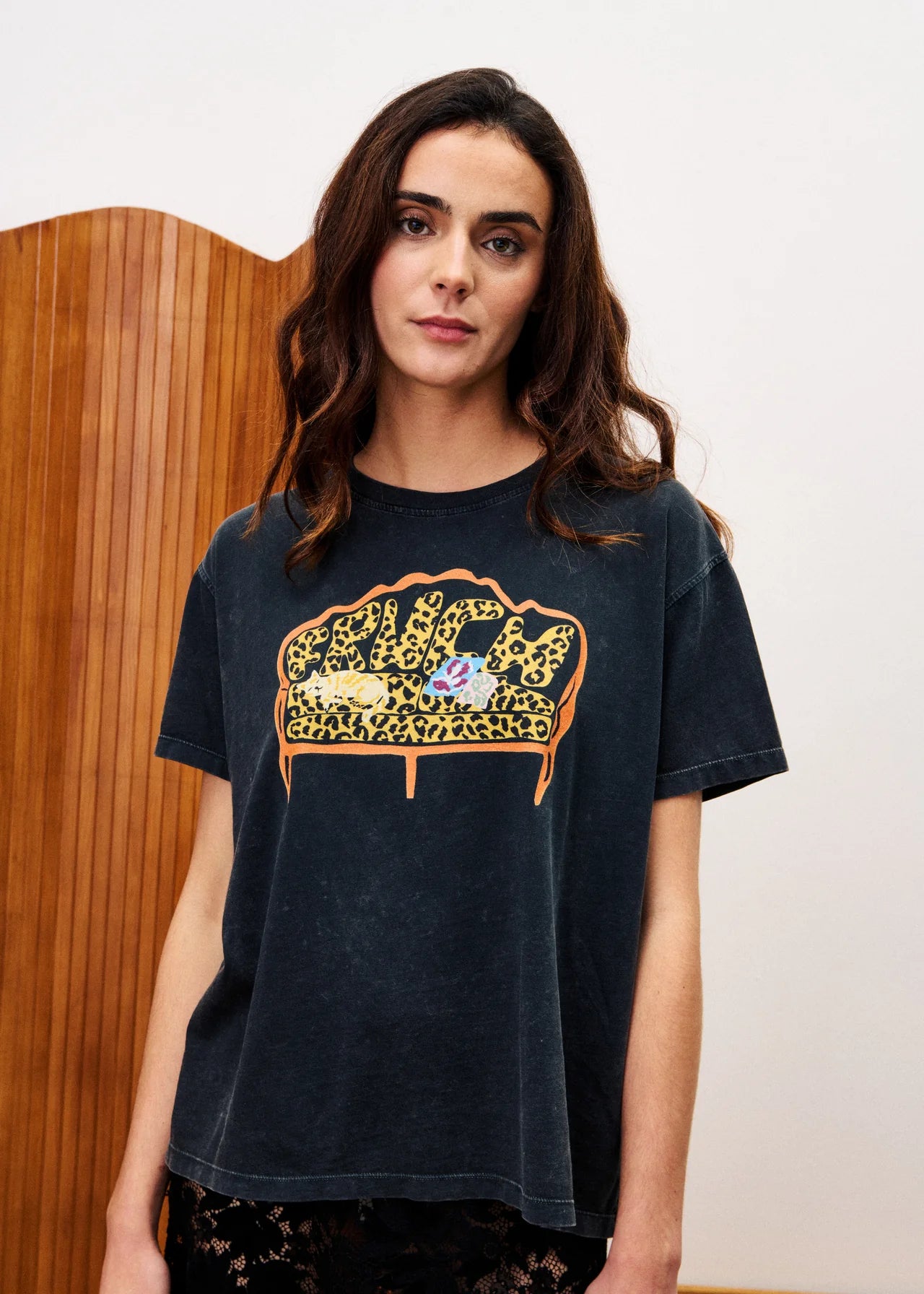 Woman wearing a black t-shirt with a graphic design of a leopard print couch and two people on it.