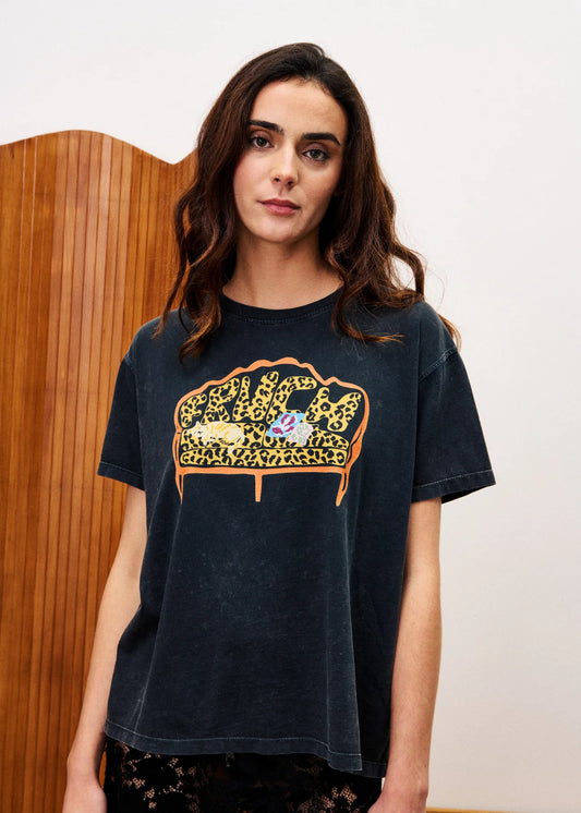 Woman wearing a black t-shirt with a graphic design of a leopard print couch and two people on it.