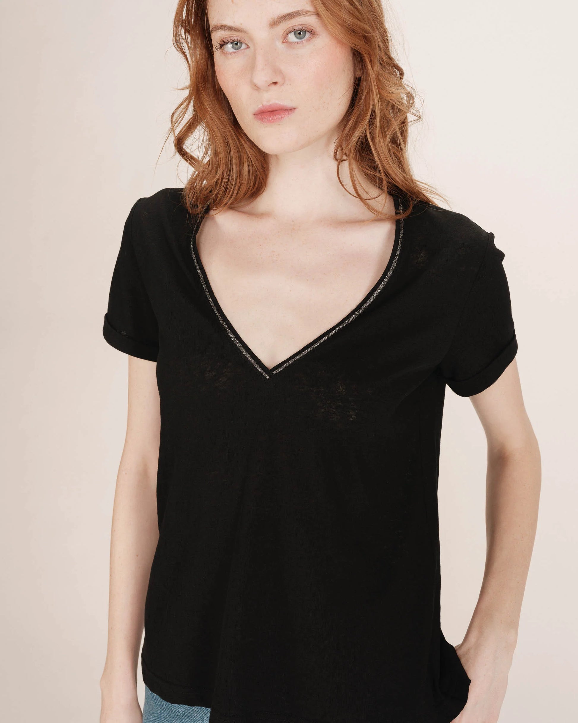 Woman wearing a black velvet top against a beige background