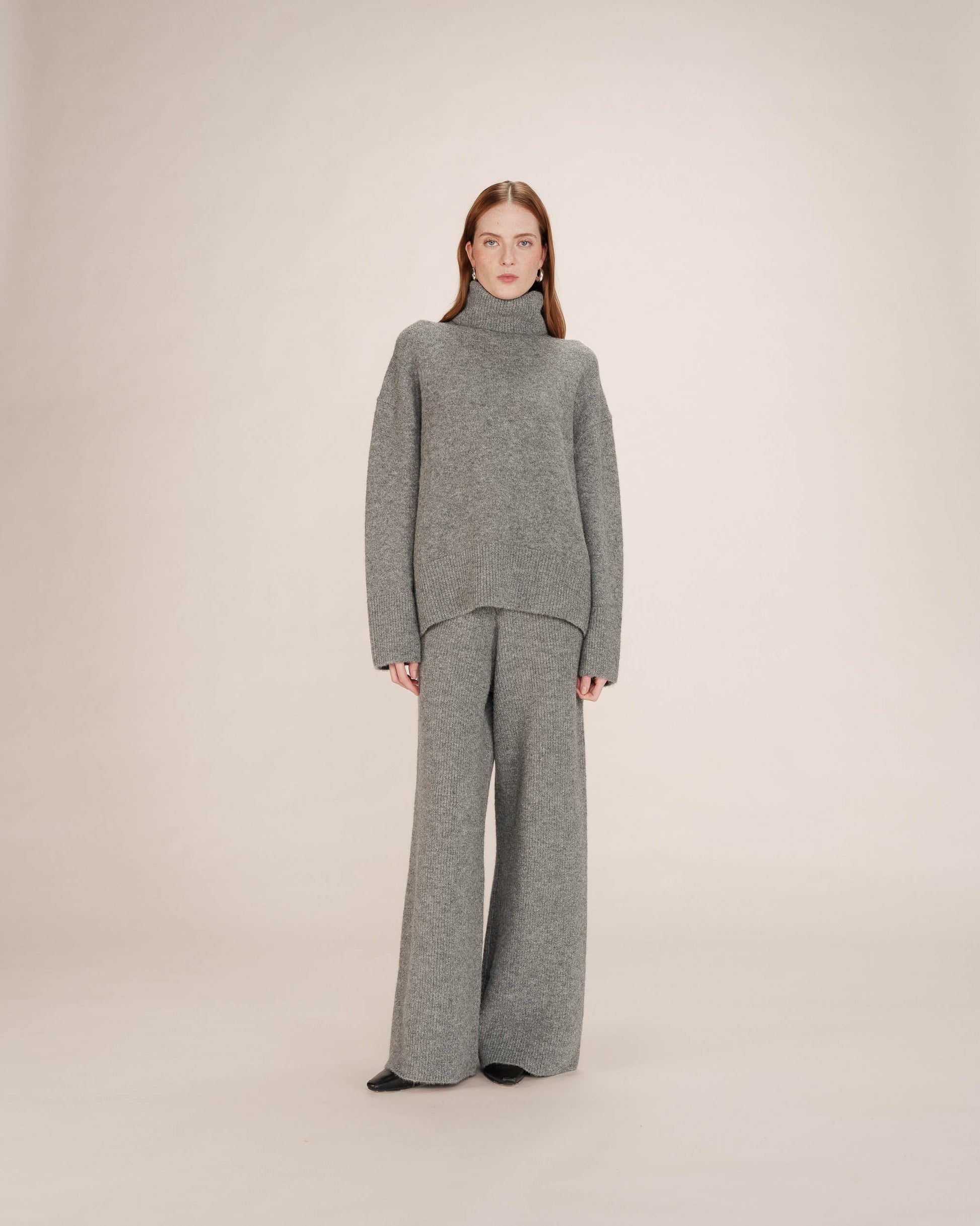 Woman wearing a gray knit outfit on a plain background