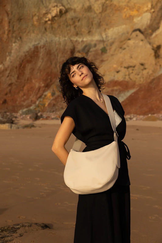 Woman in black dress with Cross body handbag in stone colour on a beach