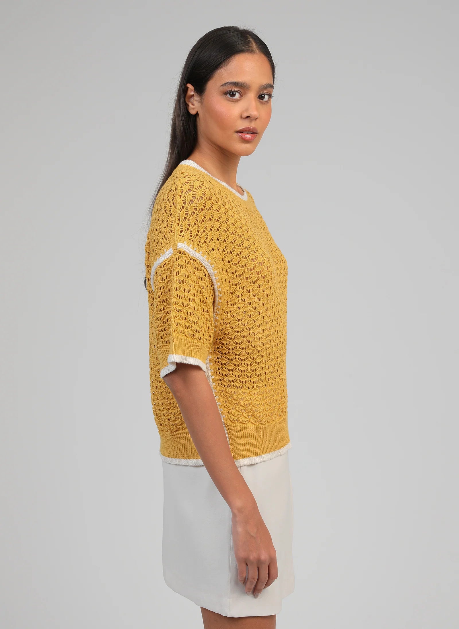 Woman wearing a yellow knitted sweater on a gray background