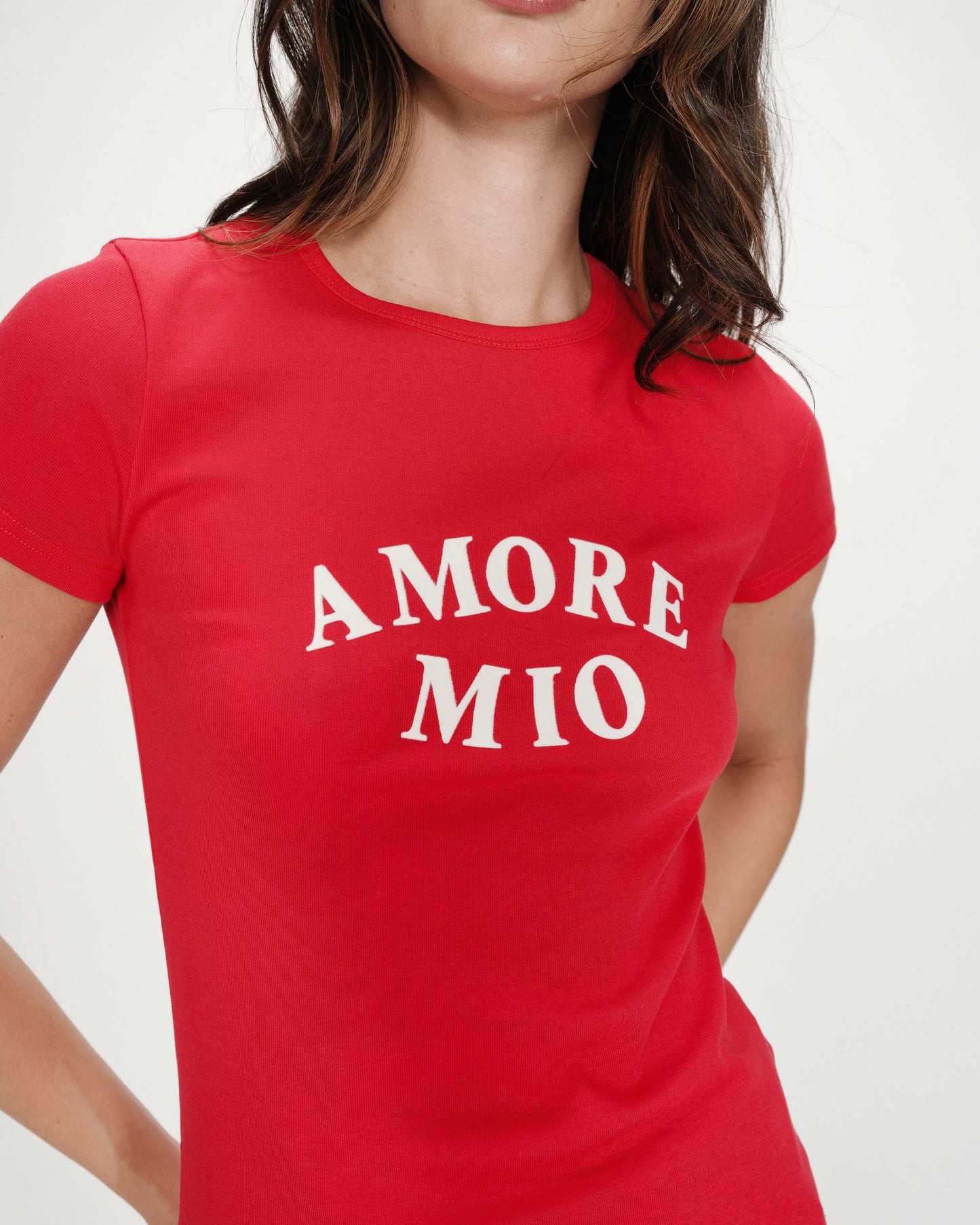 Red t-shirt with 'AMORE MIO' text worn by a person on a white background