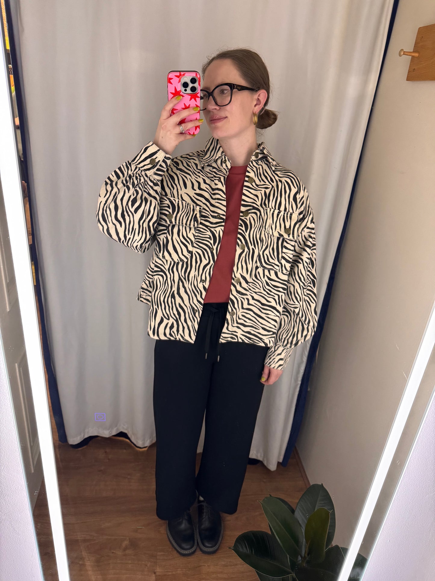 Person wearing a zebra print shirt and black pants taking a mirror selfie.