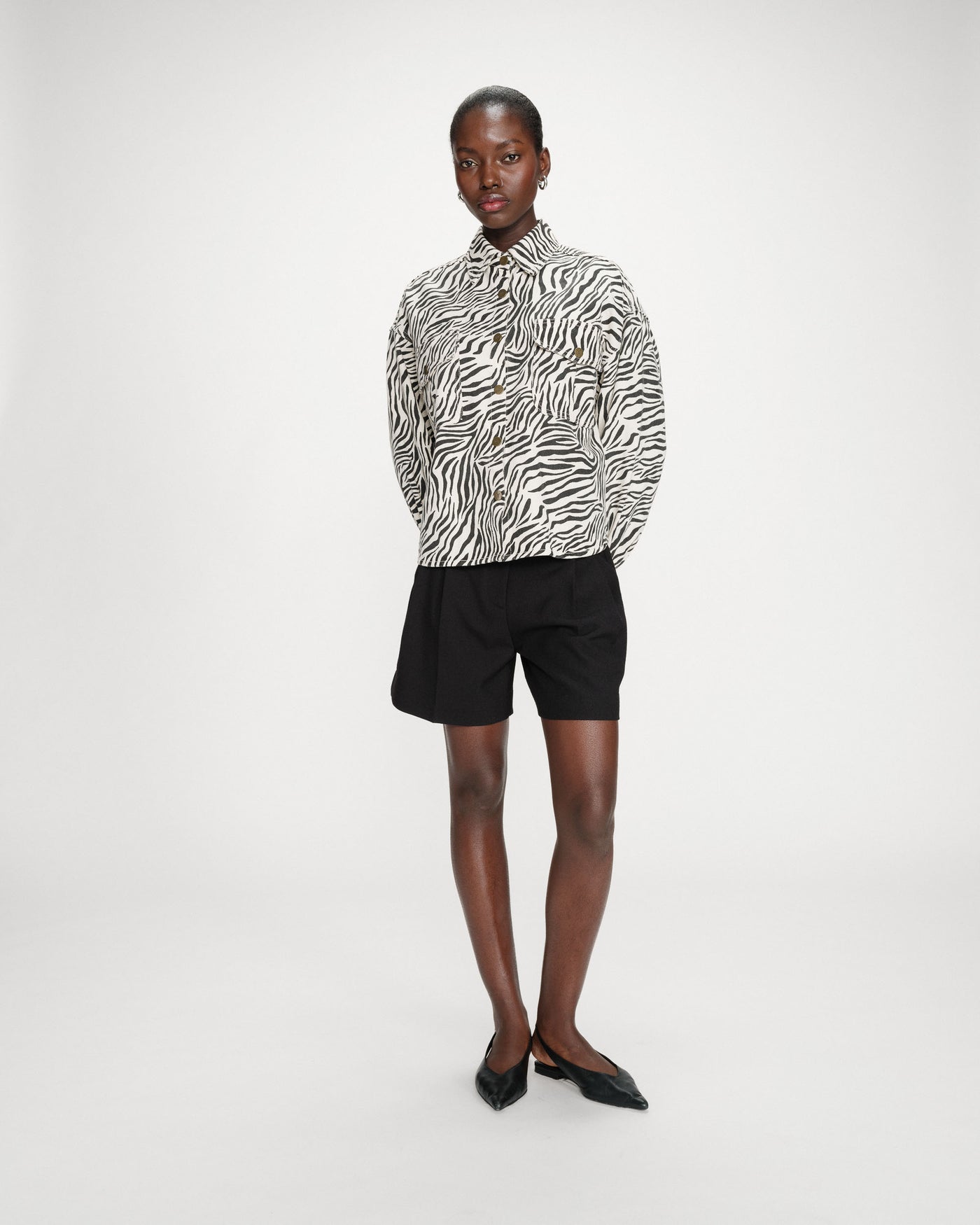 Person wearing a zebra print shirt and black shorts on a white background