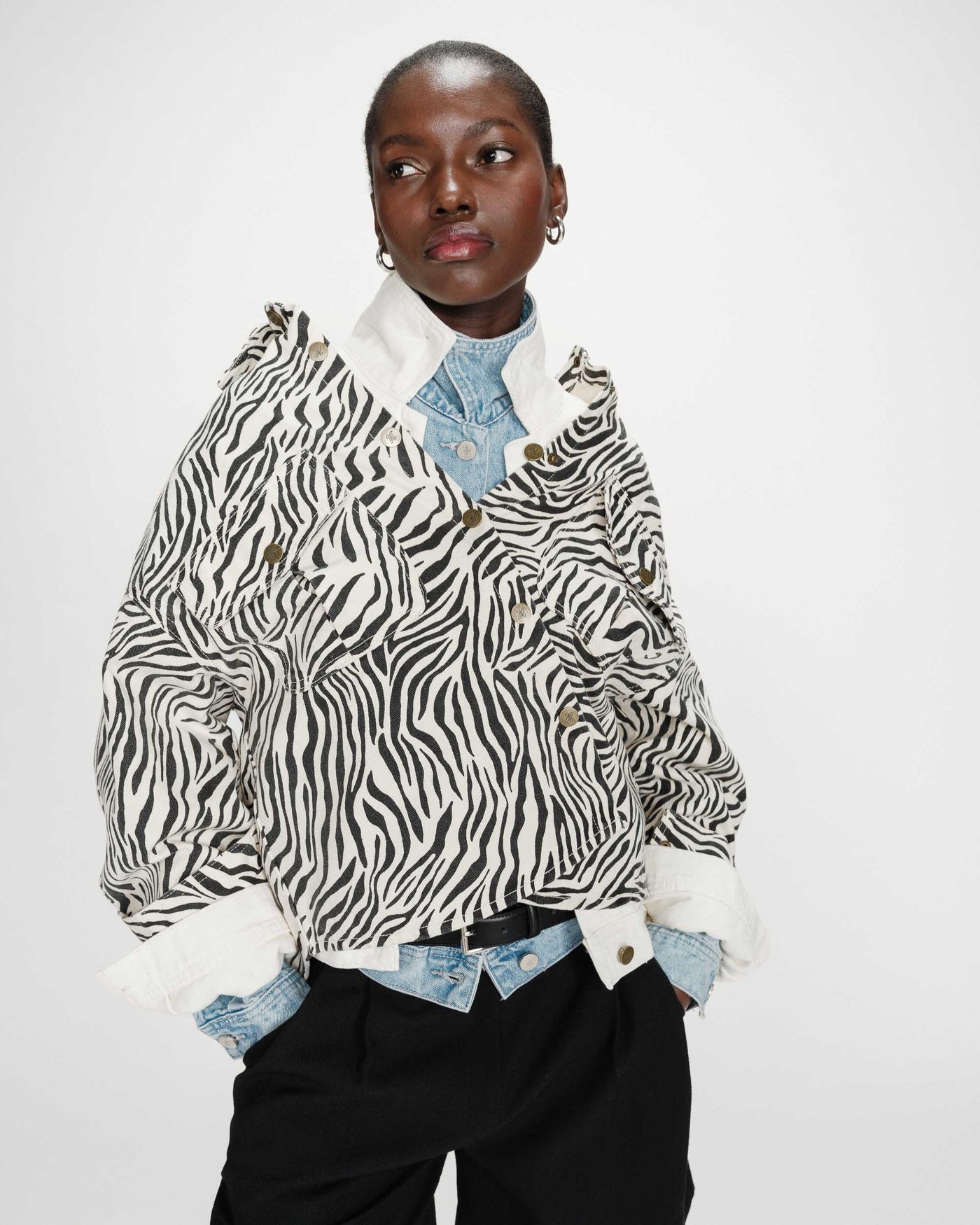 Person wearing a zebra print jacket over a denim shirt on a white background