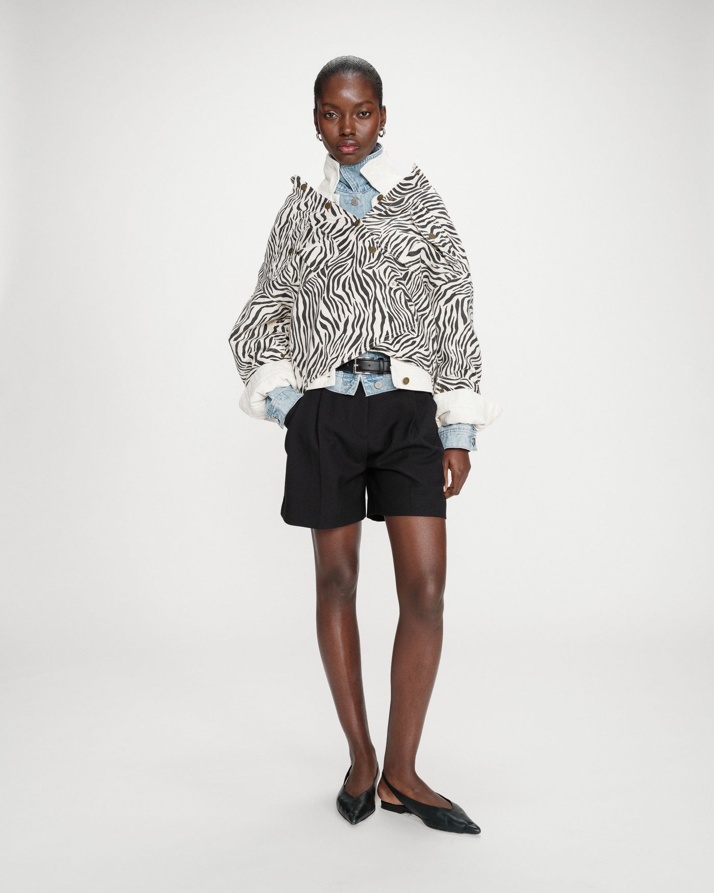 Person wearing a zebra print jacket and black shorts on a white background