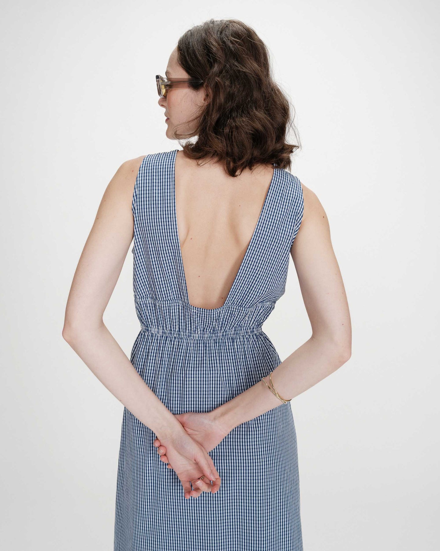 Woman wearing a blue checkered dress with an open back on a white background