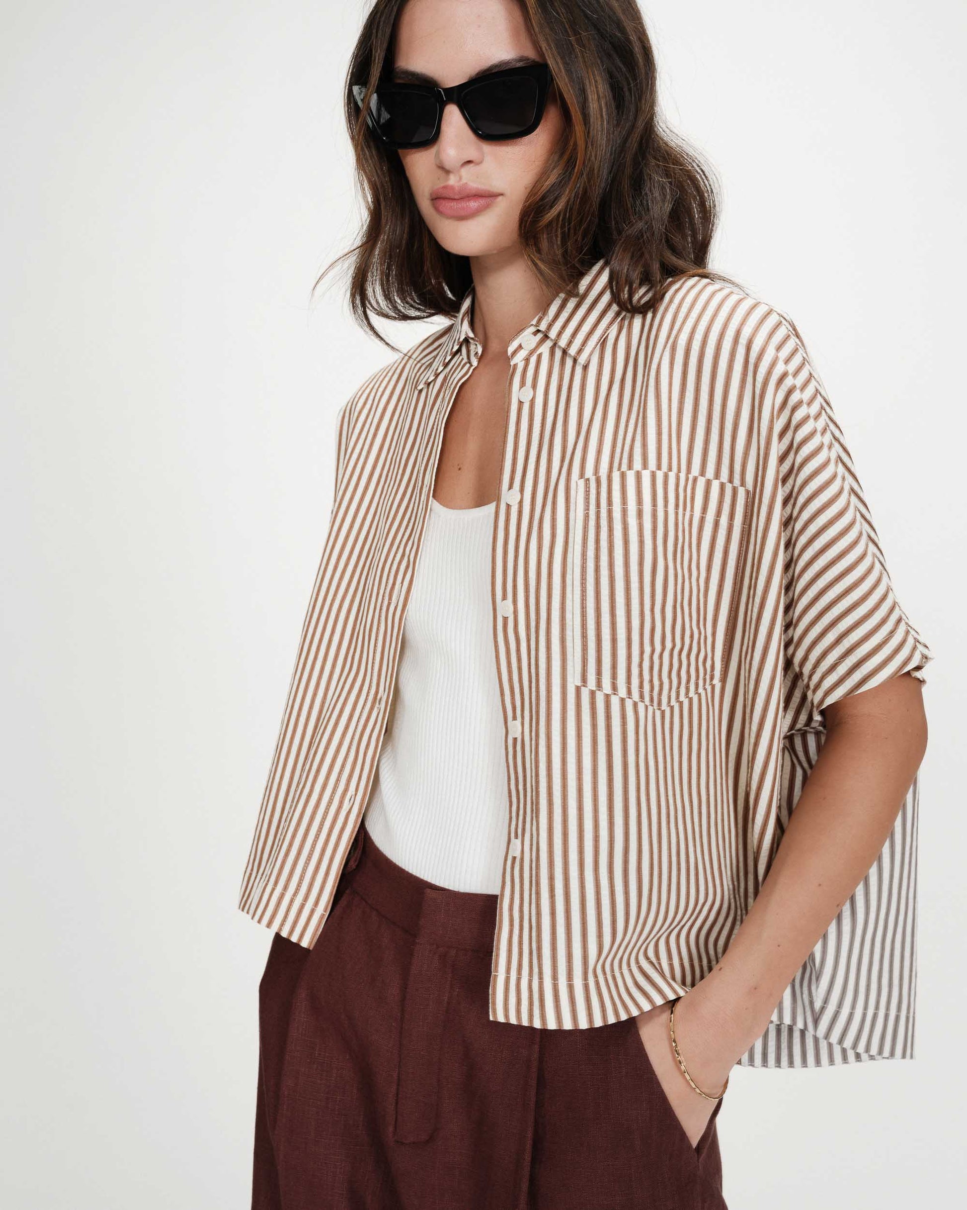 Woman wearing a striped shirt and sunglasses on a white background