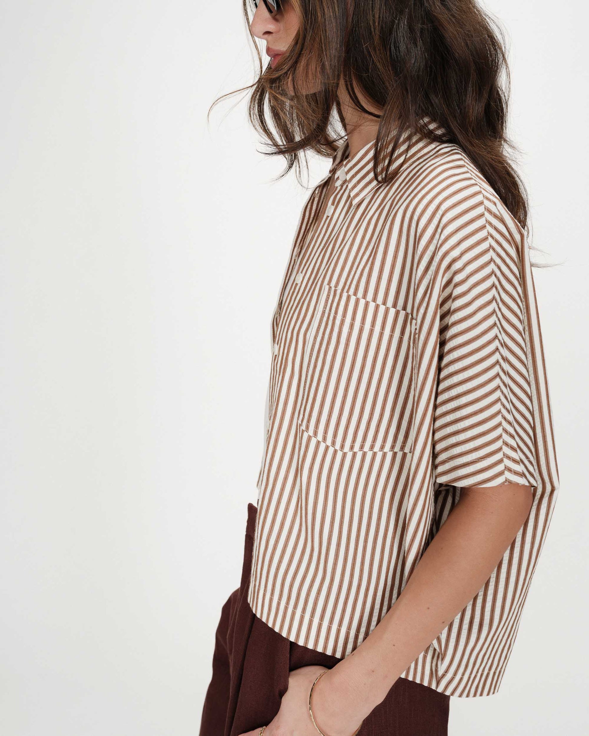 Person wearing a brown and white striped shirt with a neutral background