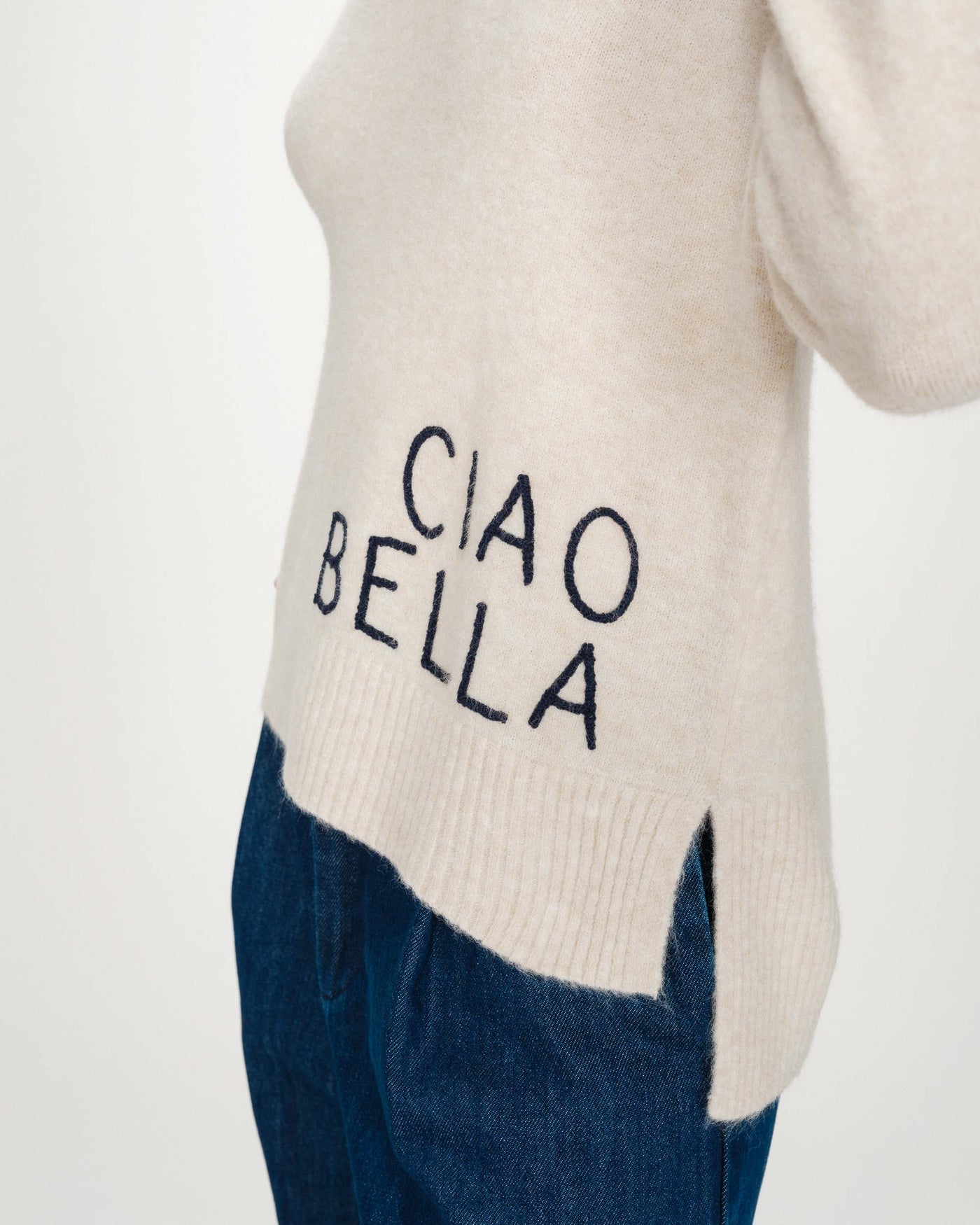 Beige sweater with 'CIAO BELLA' text and blue pants on a white background
