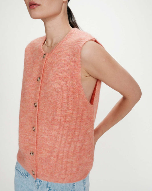 Woman wearing a pink sleeveless knitted vest on a plain background