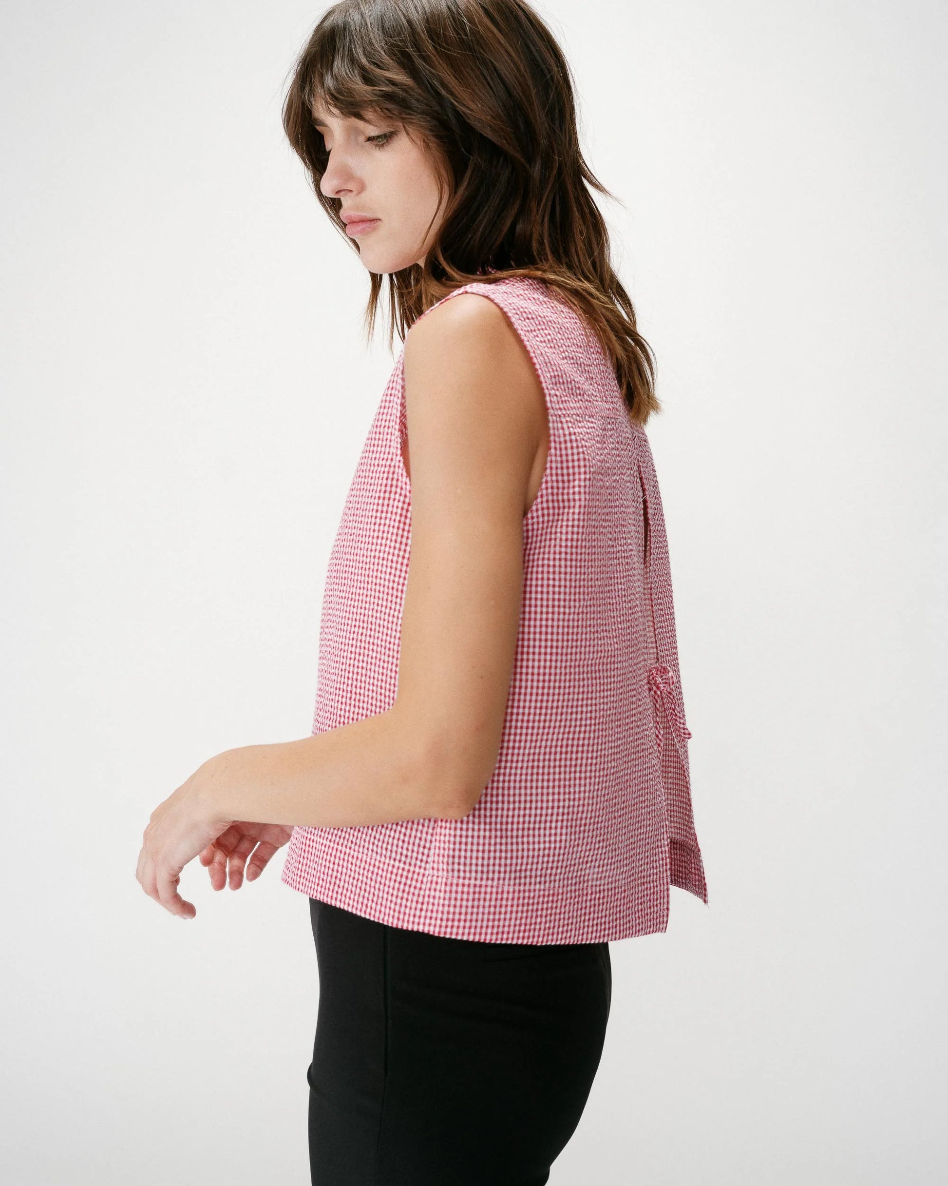 Woman wearing a red and white checkered sleeveless top on a white background