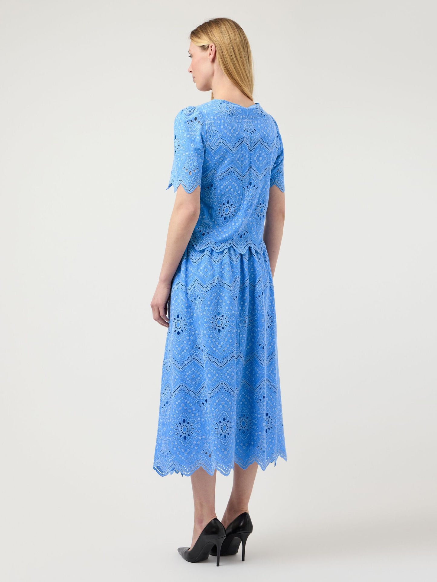 Woman wearing a blue lace dress on a white background
