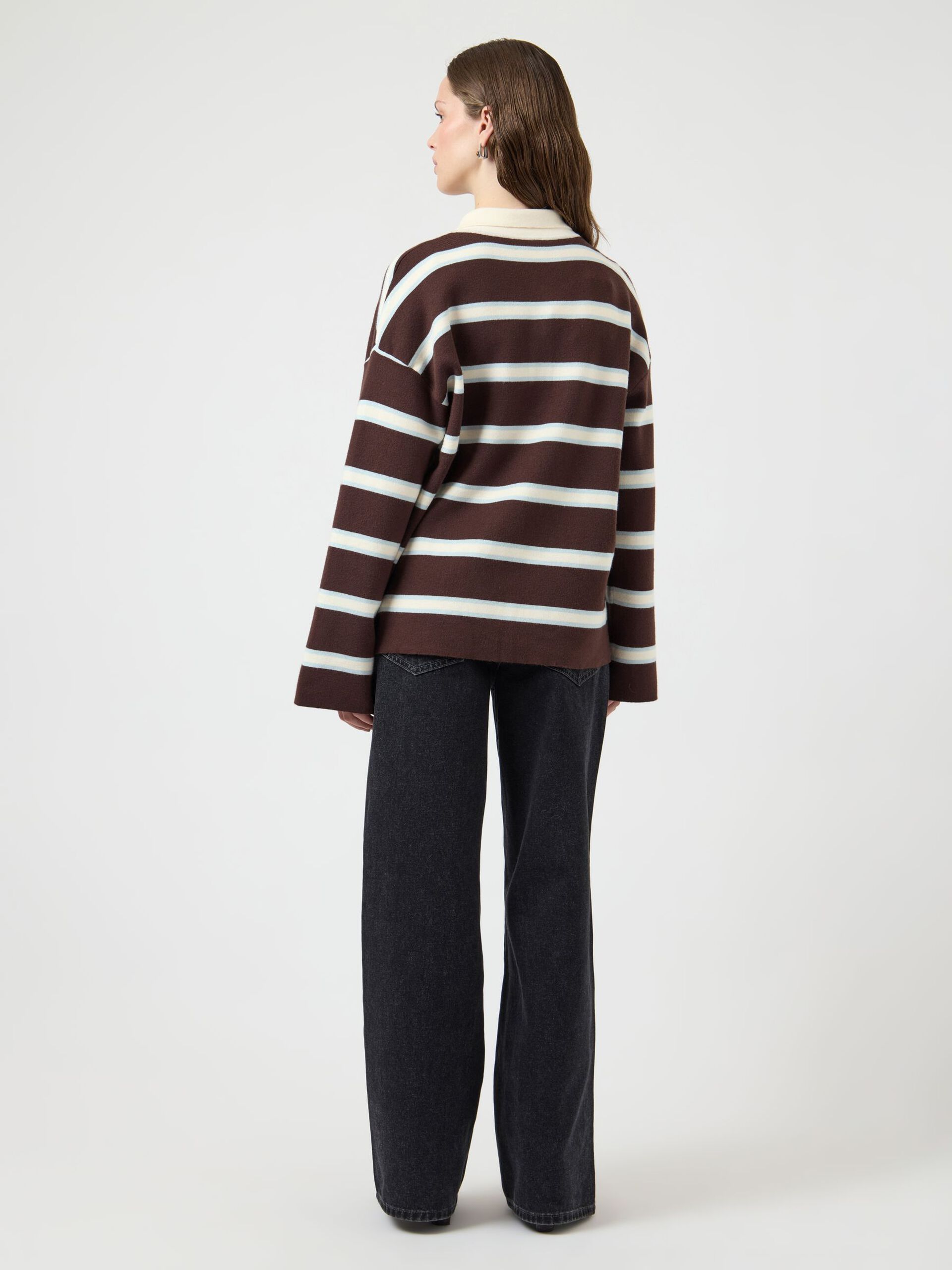 Person wearing a brown and white striped sweater with black pants on a white background