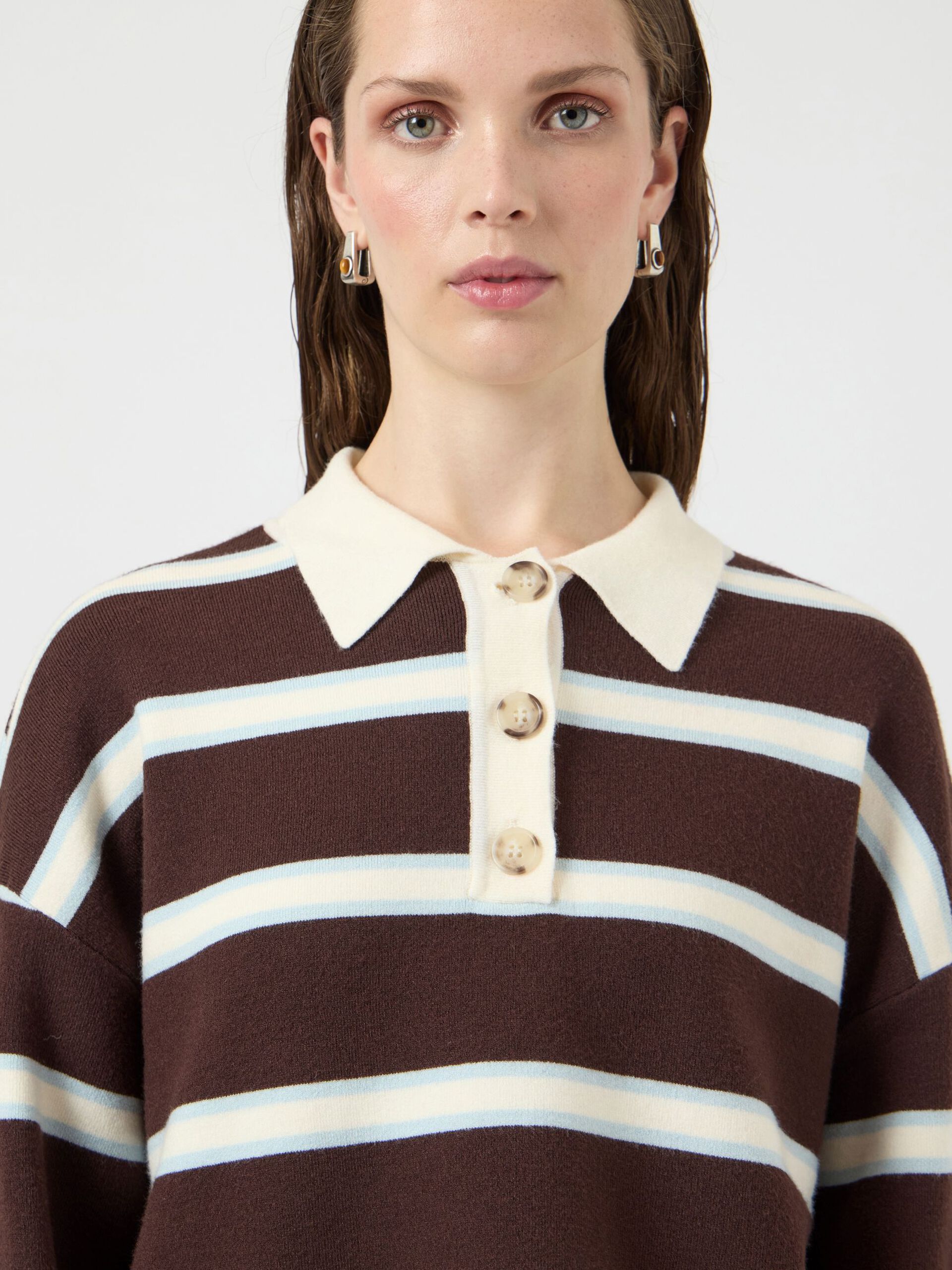 Woman wearing a brown and white striped sweater with a plain background