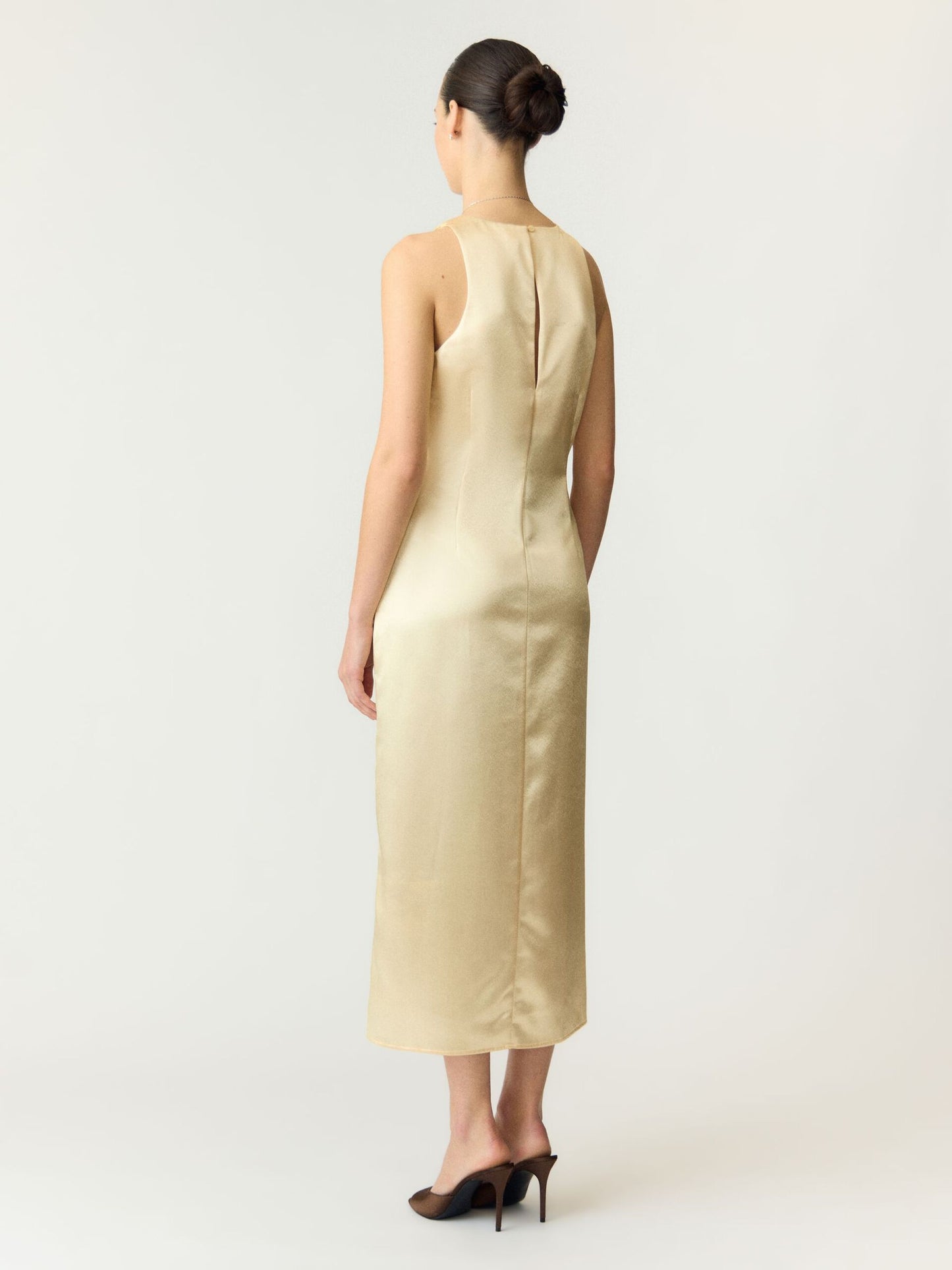 Woman wearing a beige sleeveless dress on a white background