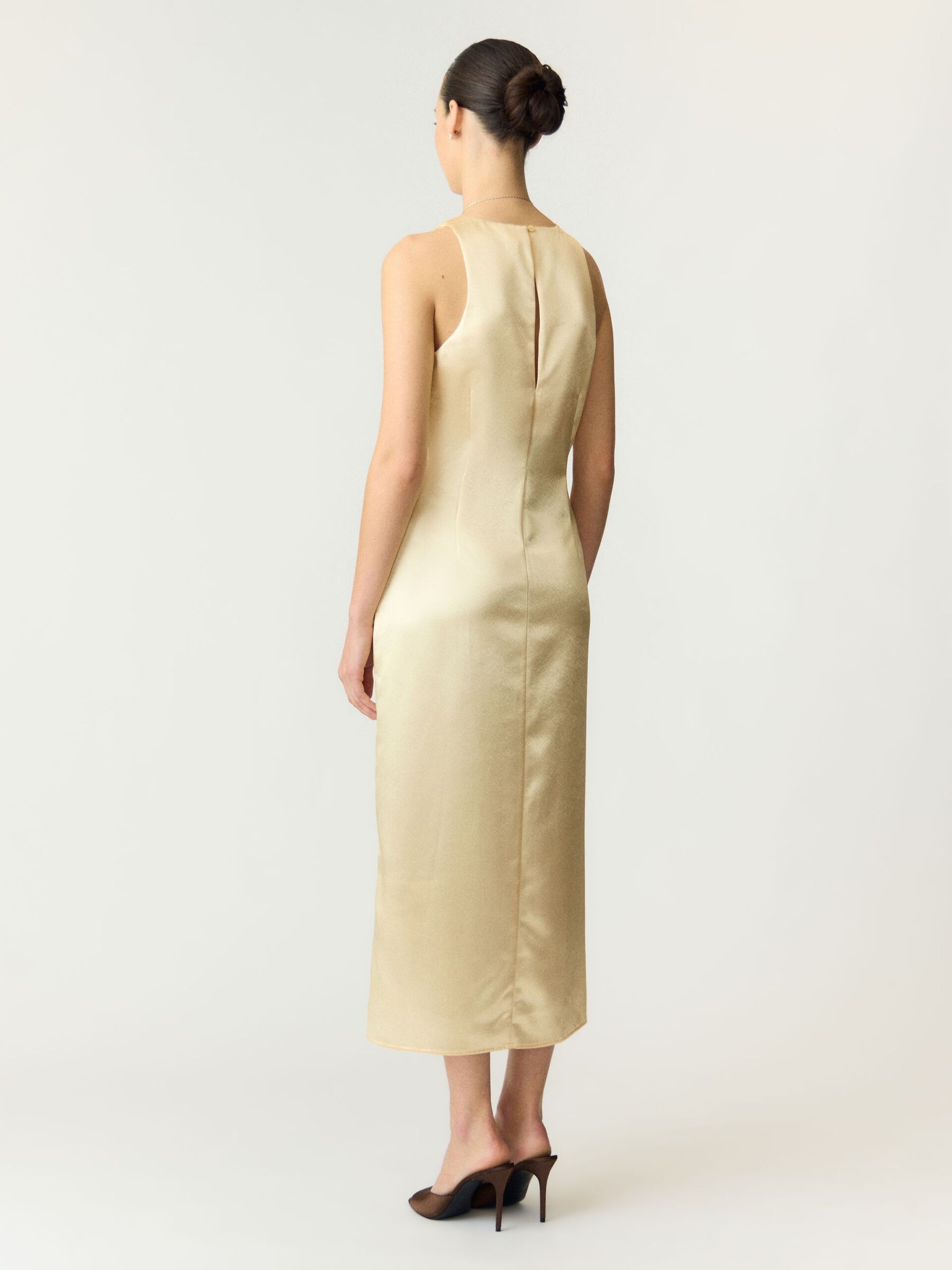 Woman wearing a beige sleeveless dress on a white background