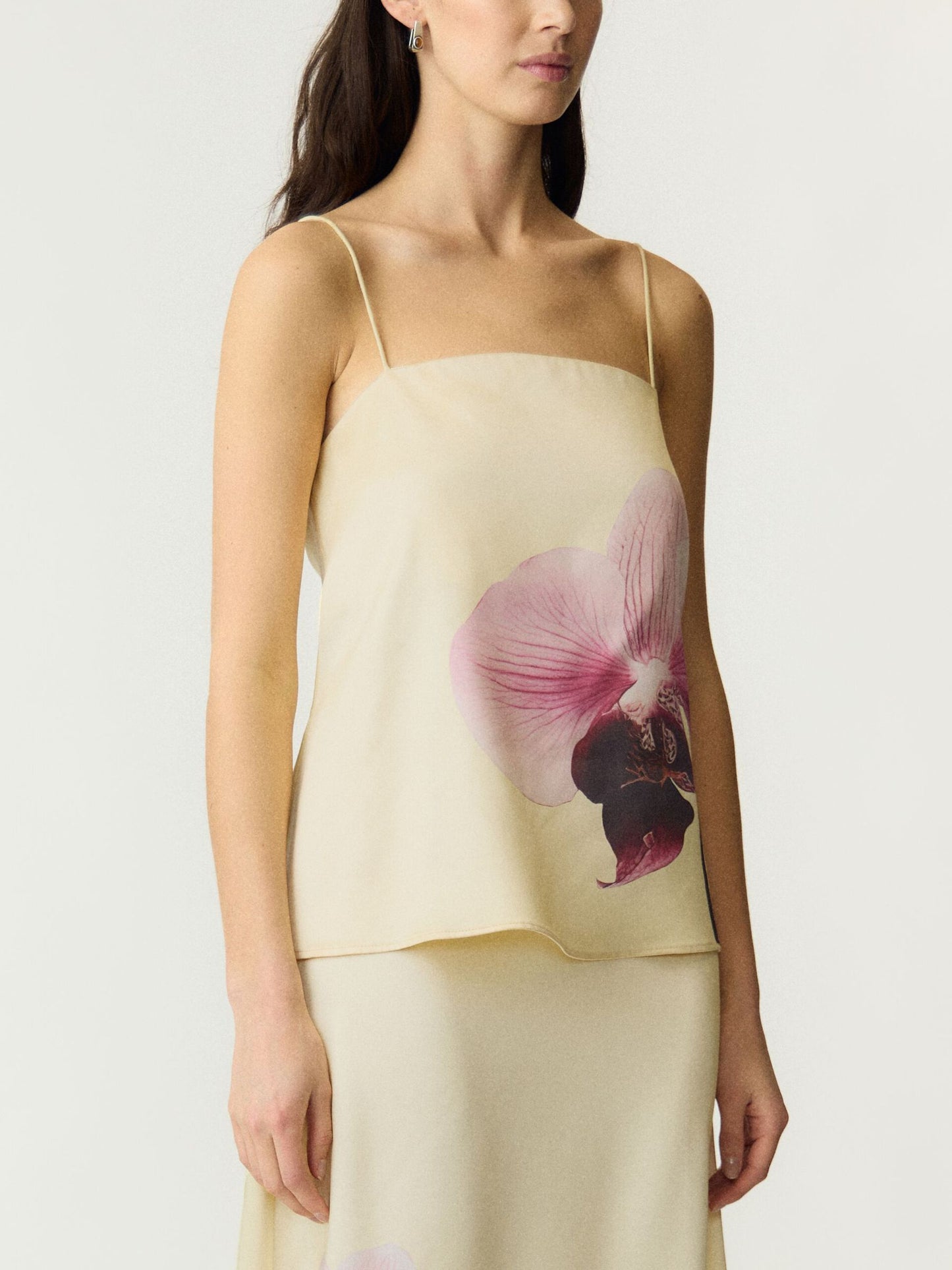 Pale yellow strappy top with pink floral print on a white background