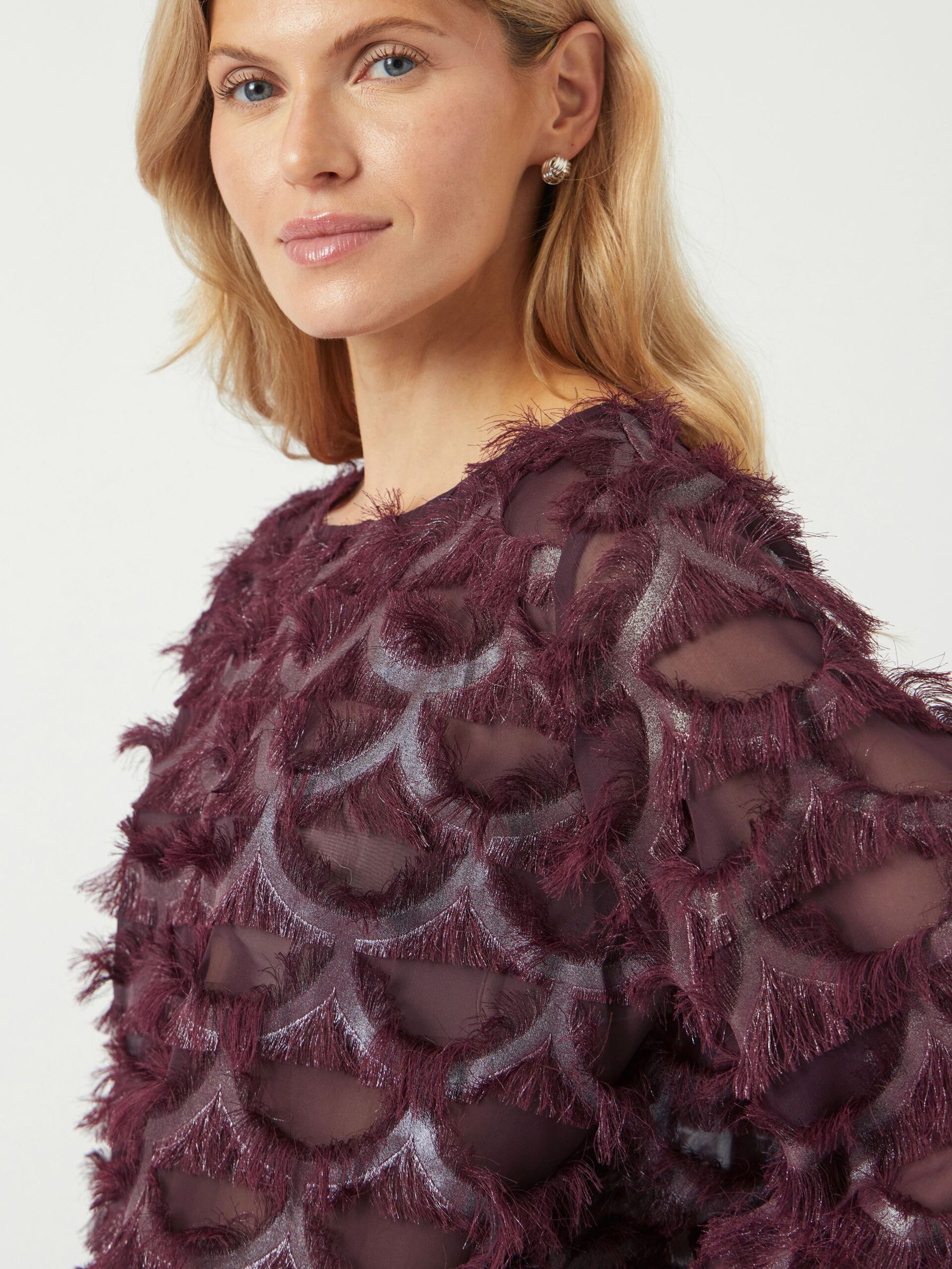 Woman wearing a burgundy textured top against a white background