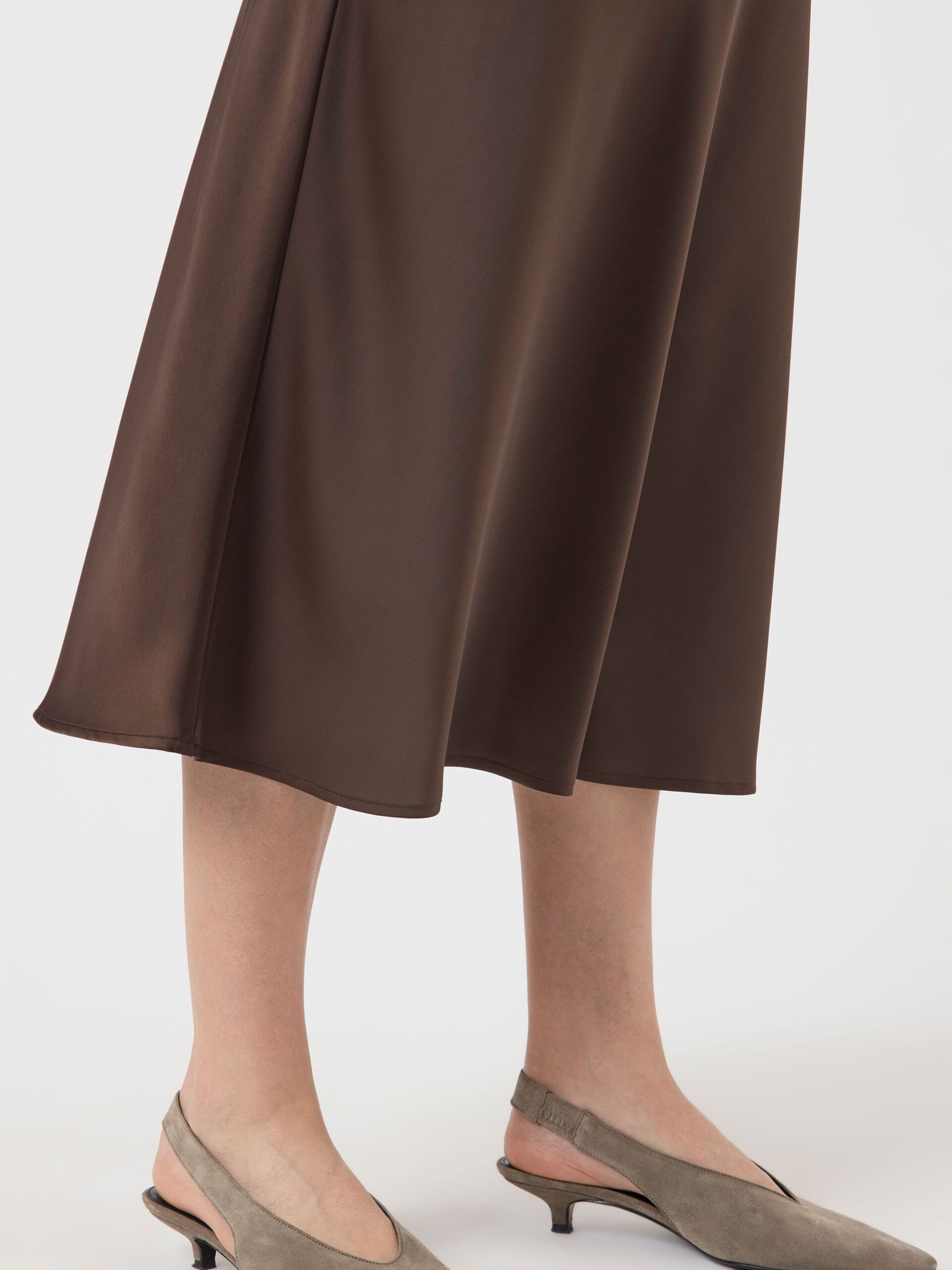 Woman wearing a brown skirt and beige top on a white background