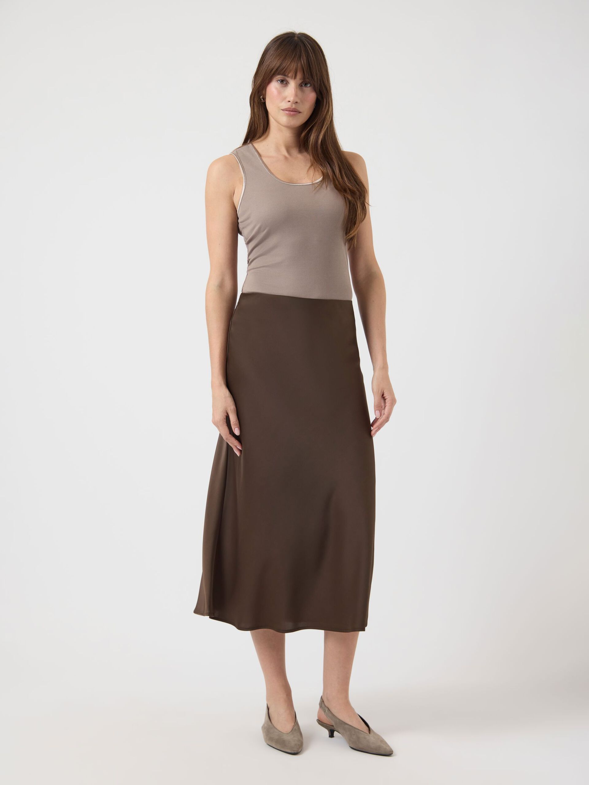 Woman wearing a brown skirt and beige top on a white background
