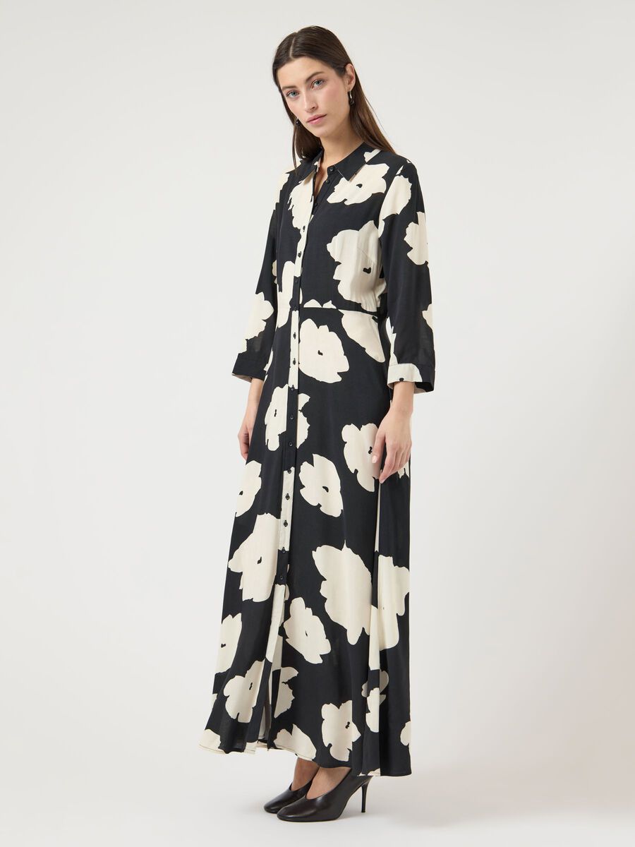 Woman wearing a black dress with white floral pattern on a white background