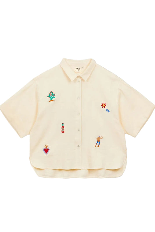 Beige shirt with colorful embroidered designs on a white background