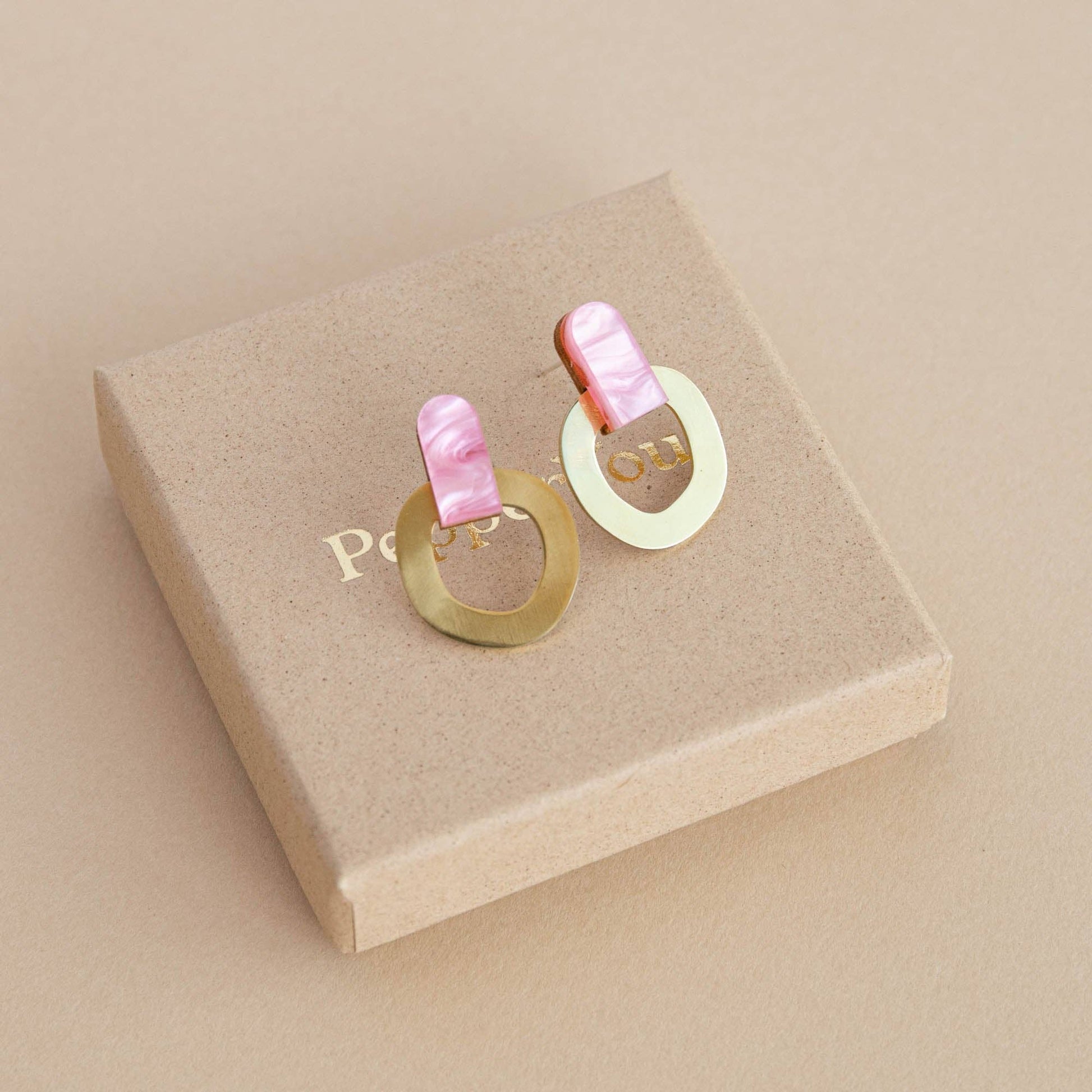 Pair of earrings on a beige jewelry box with 'Polo' branding.