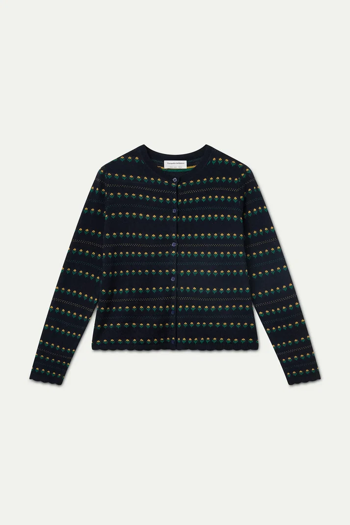 A long-sleeve knit cardigan with a dark navy base and a repeating horizontal pattern of small green, yellow, and orange motifs, laid flat against a light gray background.