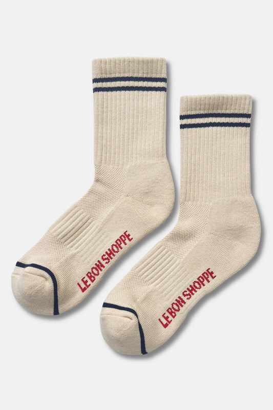 A pair of cream-colored crew socks with navy blue stripes near the cuff and red 'LEBON SHOPPE' branding printed on the sole, displayed against a light gray background.