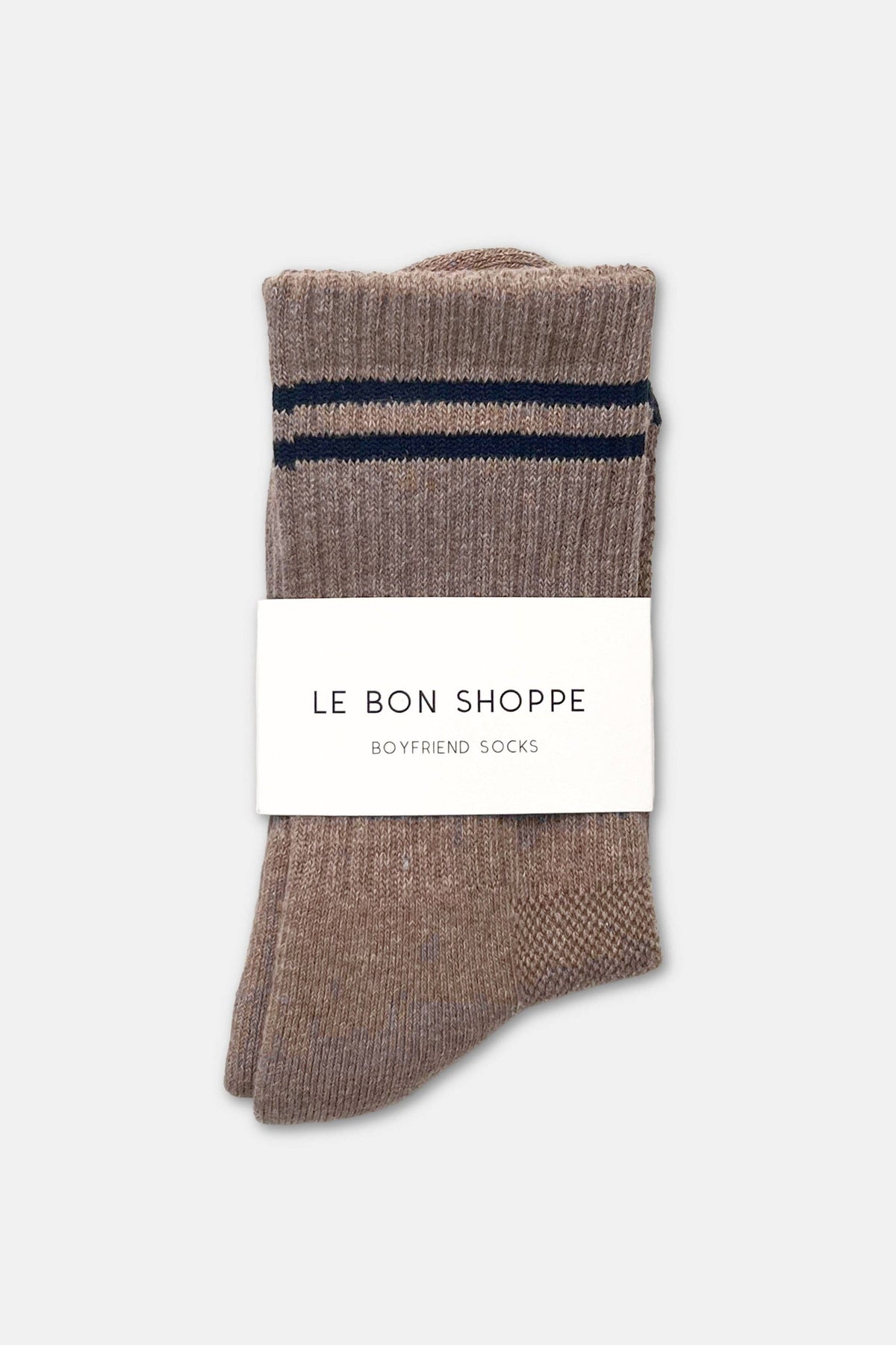 A pair of brown ribbed knit socks with two navy blue horizontal stripes near the cuff, wrapped in a white paper band that reads 'LE BON SHOPPE BOYFRIEND SOCKS' on a light gray background.