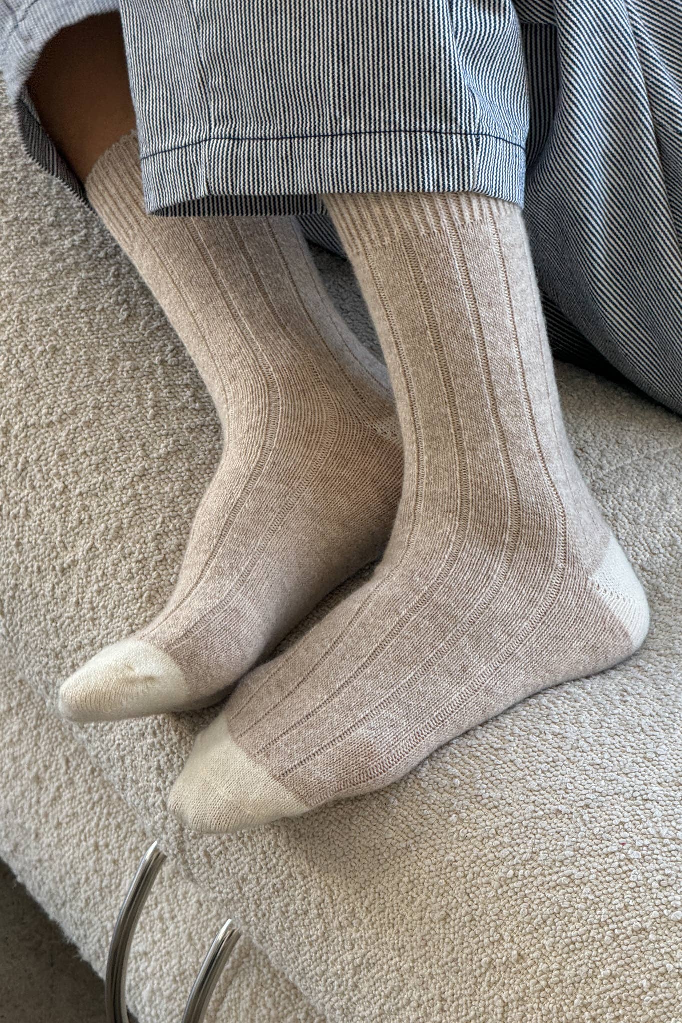Beige socks worn with gray pants on a textured surface