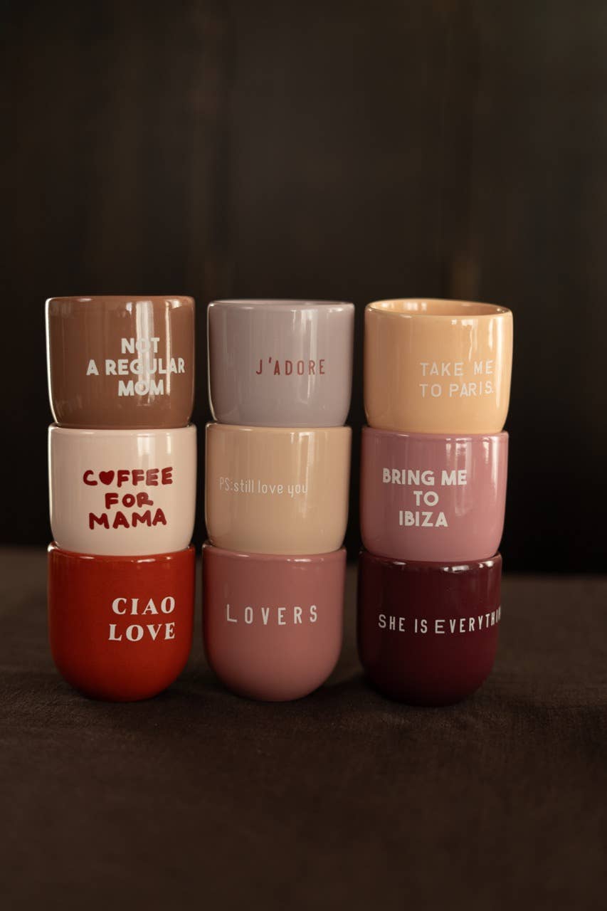 Set of eight ceramic cups with various phrases on a dark background