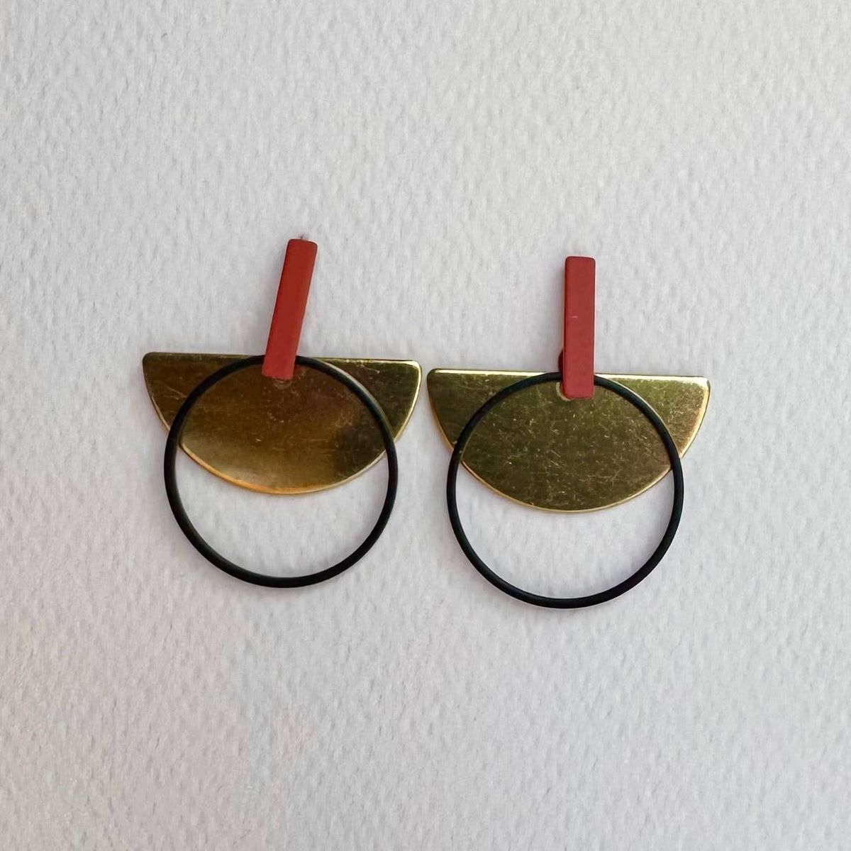 Pair of gold cat-shaped hair ties with red bands on a white background