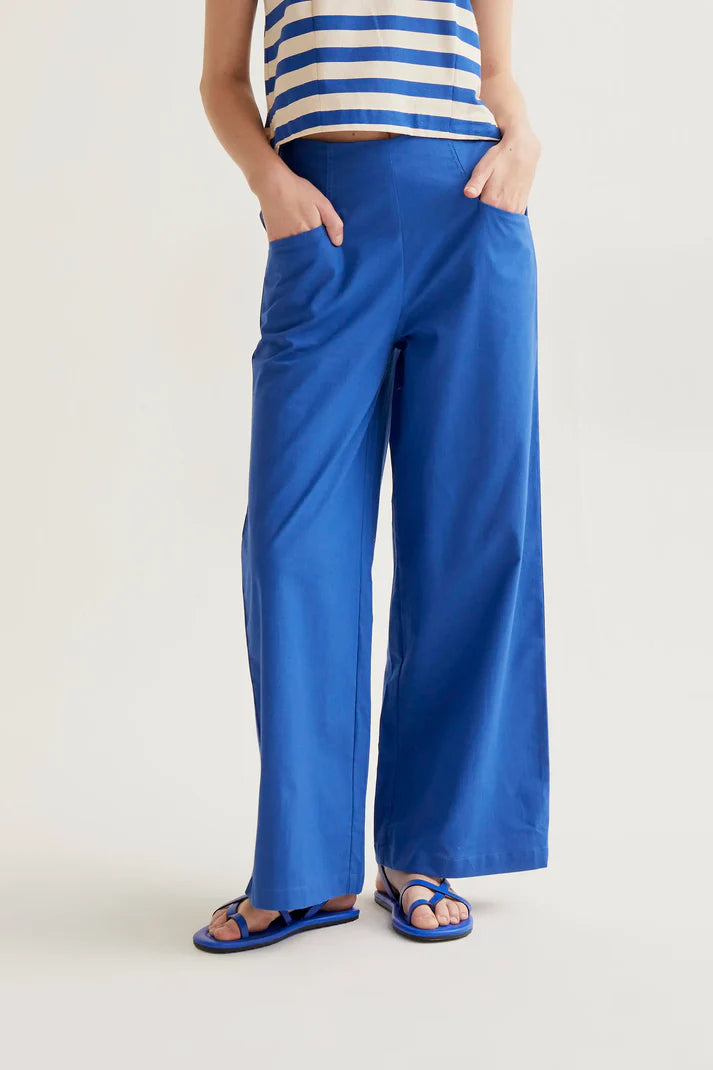 Person wearing blue wide-leg pants and a striped top on a light background