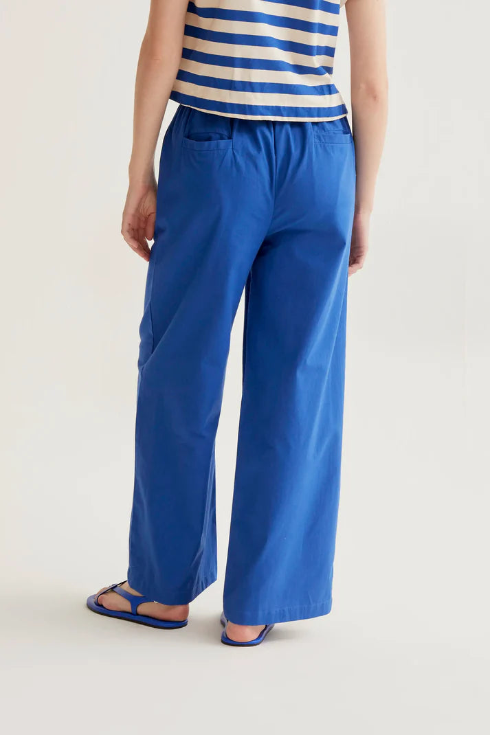 Person wearing blue wide-leg pants and a striped top on a white background