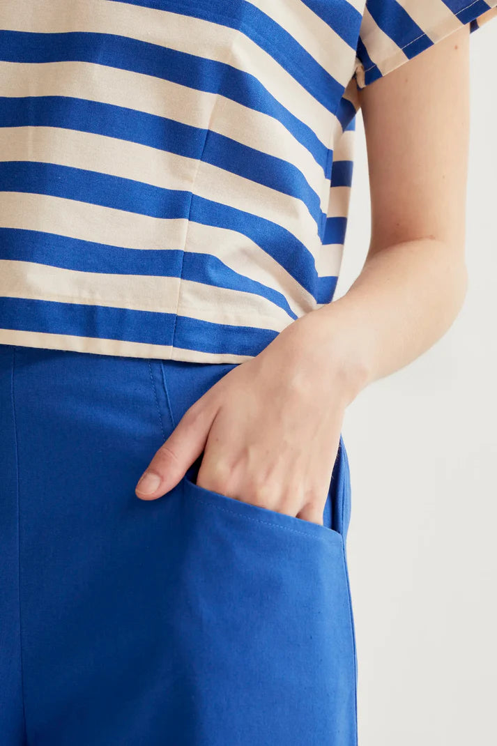 Person wearing a blue and white striped shirt with a blue skirt on a light background