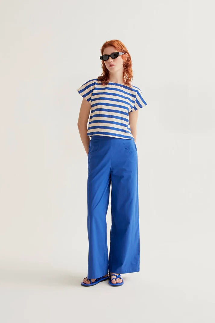 Woman wearing a blue and white striped shirt with wide-leg pants on a white background