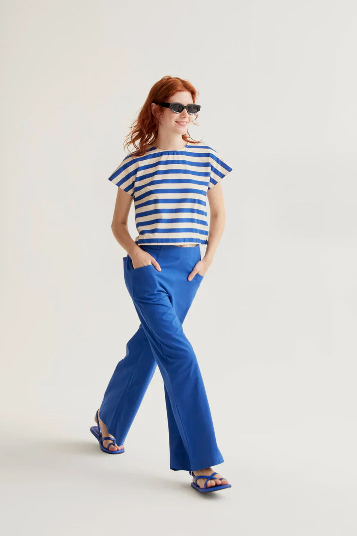 Woman wearing a blue and white striped top and blue pants on a light background