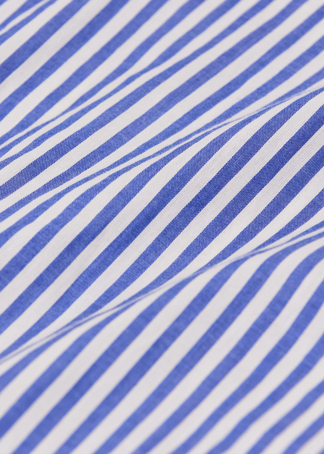 A close-up of a blue and white striped fabric with a soft, draped texture.